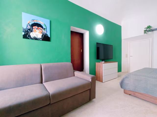 Soggiorno con divano, letto e televisione de Le Stanze del Corso