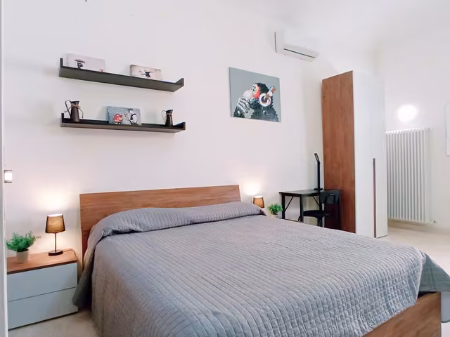 Camera con mensole in legno e letto matrimoniale