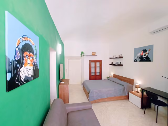 Camera con parete verde e letto matrimoniale ad Ascoli Piceno